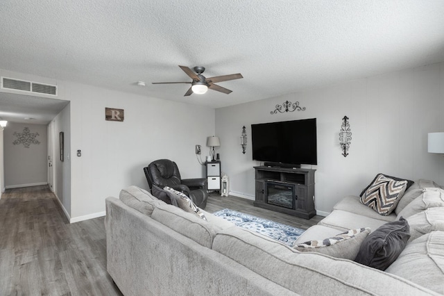 living area with a ceiling fan, visible vents, a textured ceiling, and wood finished floors