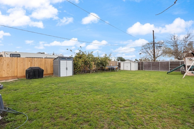 view of yard with a storage shed, a playground, a fenced backyard, and an outdoor structure