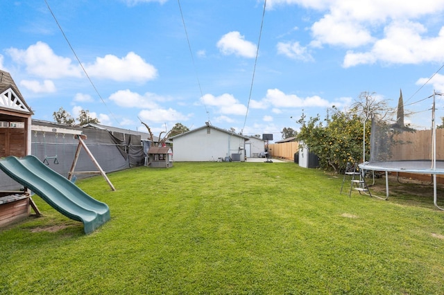 view of yard with a trampoline, a playground, and a fenced backyard