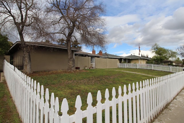 view of side of property with a lawn, a fenced backyard, and stucco siding