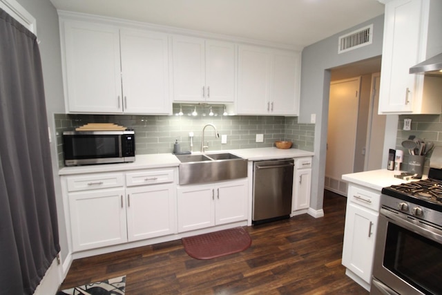 kitchen with wall chimney range hood, appliances with stainless steel finishes, a sink, light countertops, and visible vents
