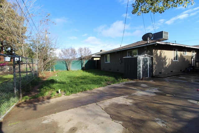 view of side of home with a yard, crawl space, fence, and cooling unit
