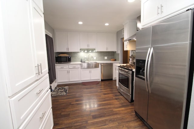 kitchen featuring a sink, white cabinetry, appliances with stainless steel finishes, decorative backsplash, and dark wood-style floors