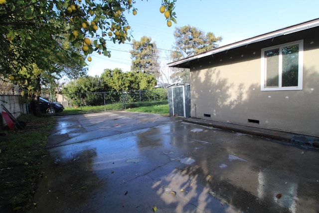 view of patio with a storage shed, fence, and an outbuilding