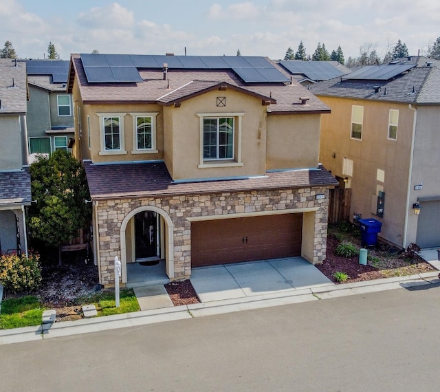 view of front facade with stucco siding, a shingled roof, an attached garage, roof mounted solar panels, and driveway