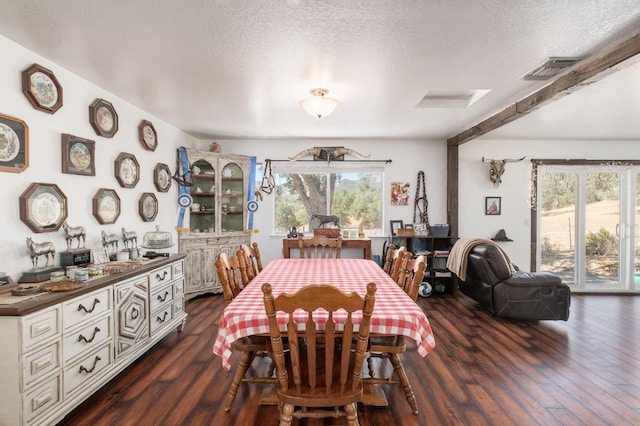 dining space featuring dark wood-style floors, a textured ceiling, and visible vents