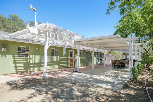 back of house featuring a pergola, fence, and stucco siding