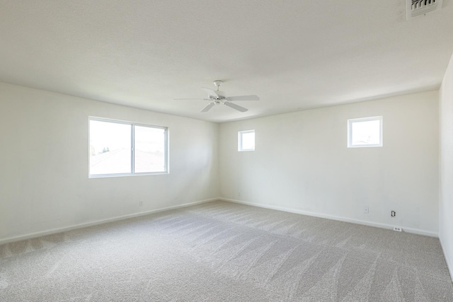 empty room with light carpet, baseboards, visible vents, and a ceiling fan