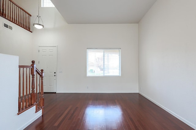 spare room featuring stairs, visible vents, baseboards, and wood finished floors