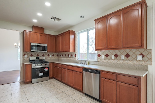 kitchen featuring stainless steel appliances, light countertops, visible vents, backsplash, and a sink