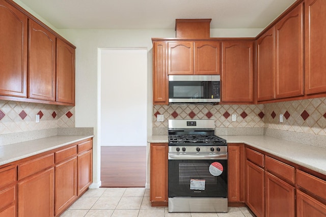 kitchen with light tile patterned floors, light countertops, appliances with stainless steel finishes, and tasteful backsplash