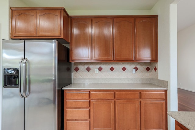 kitchen featuring brown cabinets, stainless steel fridge, and tasteful backsplash