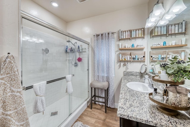 bathroom featuring a stall shower, wood finished floors, and vanity