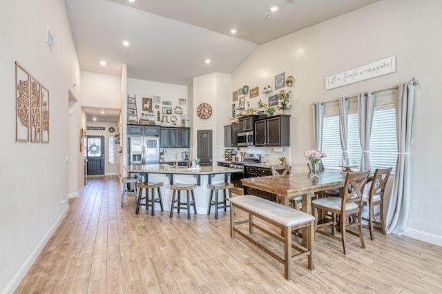 dining area with high vaulted ceiling, light wood-type flooring, plenty of natural light, and baseboards