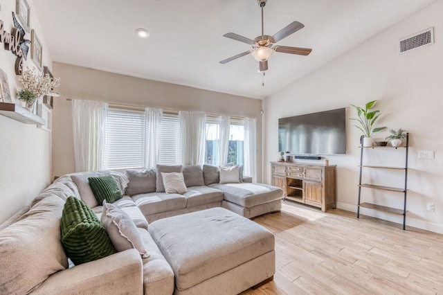 living room featuring lofted ceiling, visible vents, baseboards, a ceiling fan, and light wood finished floors