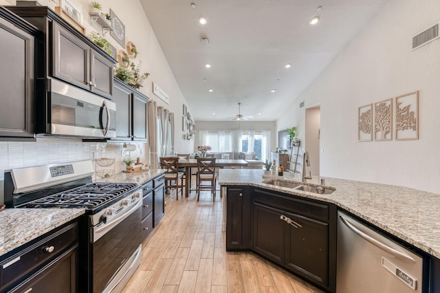 kitchen featuring stainless steel appliances, a sink, visible vents, light wood finished floors, and tasteful backsplash