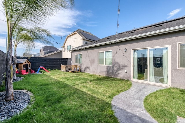 rear view of property with a fenced backyard, a lawn, and stucco siding