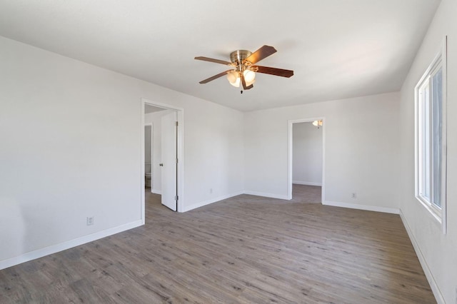 spare room with wood finished floors, a ceiling fan, and baseboards