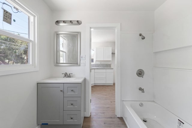 bathroom featuring wood finished floors, vanity, and bathing tub / shower combination