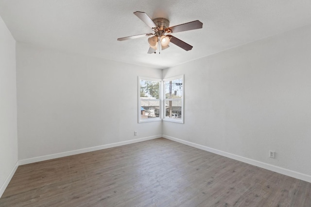 spare room featuring a ceiling fan, baseboards, and wood finished floors