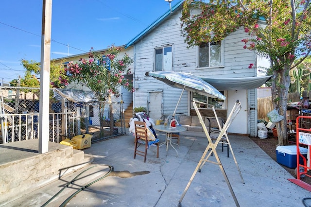 rear view of property featuring a patio, outdoor dining area, and fence