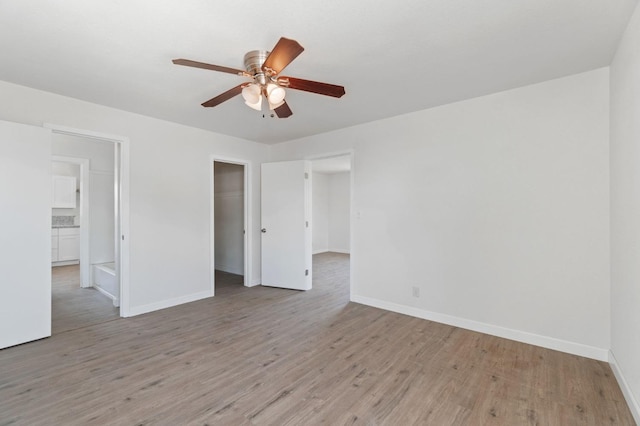 unfurnished bedroom featuring a ceiling fan, a closet, light wood-style flooring, and baseboards