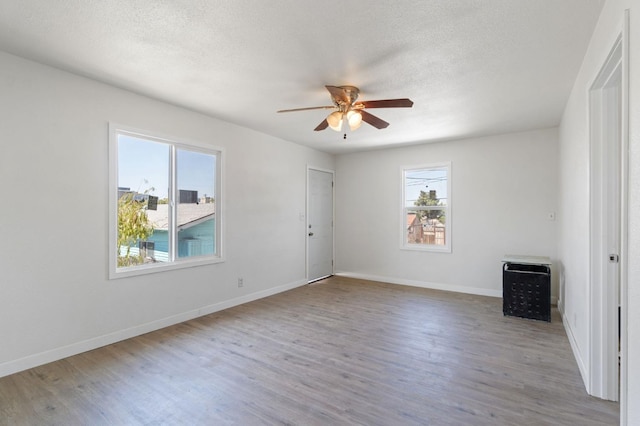 unfurnished room featuring a textured ceiling, wood finished floors, a ceiling fan, and baseboards