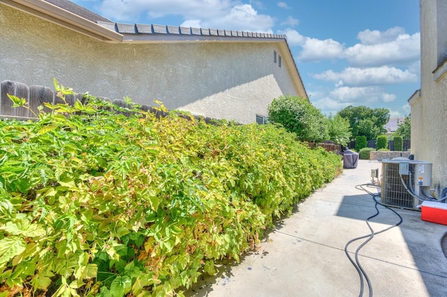 view of side of home featuring a patio, central AC, and stucco siding