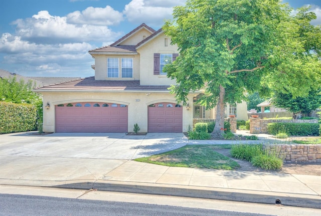 view of front facade featuring a garage, concrete driveway, a tile roof, and stucco siding