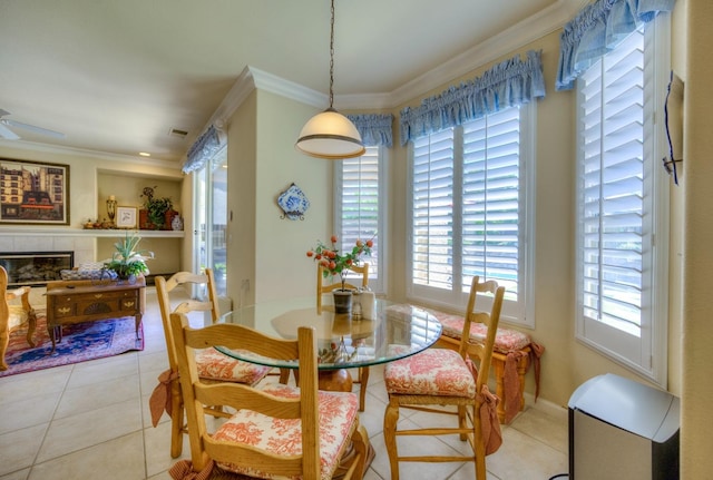 dining space featuring light tile patterned floors, crown molding, and a tile fireplace