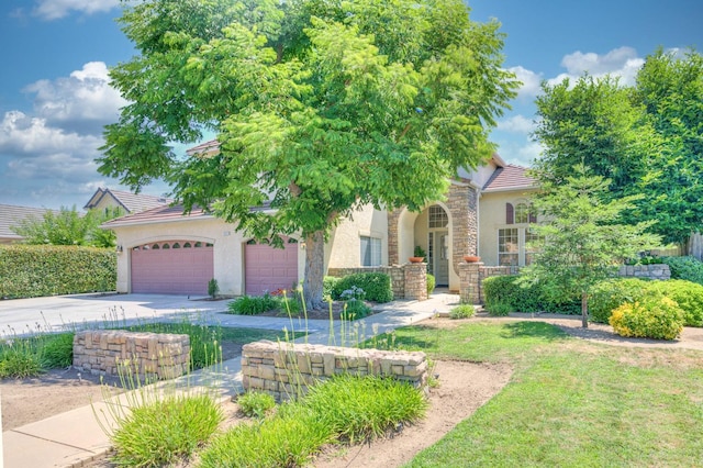 obstructed view of property with an attached garage, concrete driveway, stone siding, a tiled roof, and stucco siding