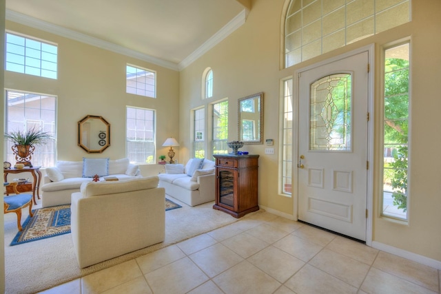 entryway with tile patterned flooring, crown molding, a towering ceiling, and baseboards