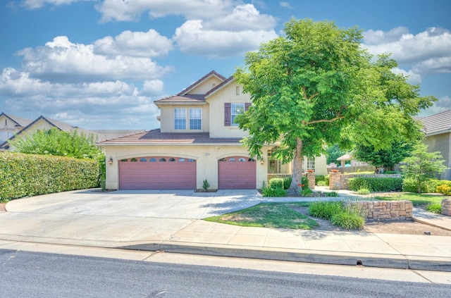 view of front of house with driveway, a tile roof, an attached garage, and stucco siding