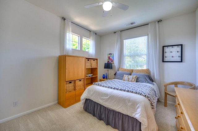 bedroom with light colored carpet, ceiling fan, visible vents, and baseboards