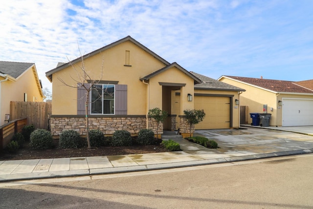 view of front of home with a garage, concrete driveway, stone siding, fence, and stucco siding