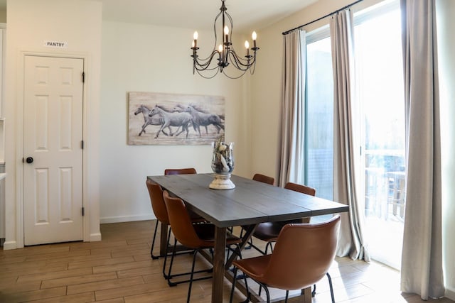 dining space with light wood-type flooring, an inviting chandelier, and baseboards