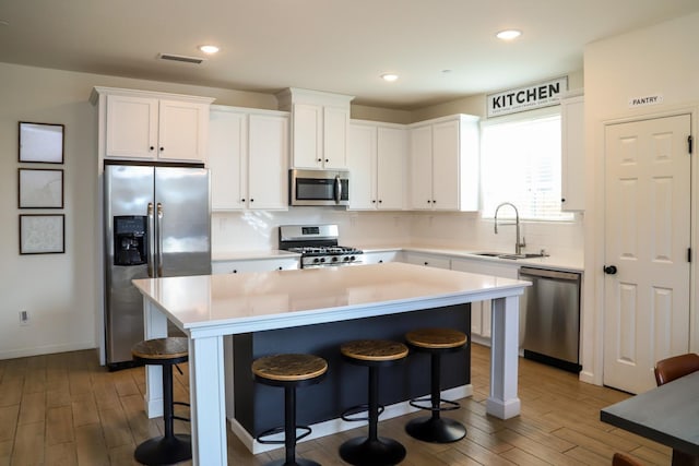 kitchen featuring visible vents, decorative backsplash, a kitchen breakfast bar, stainless steel appliances, and a sink