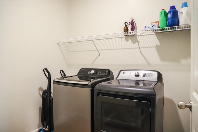 washroom featuring laundry area, baseboards, and washer and clothes dryer