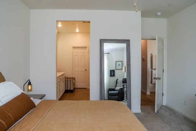 bedroom with radiator, light colored carpet, connected bathroom, and baseboards