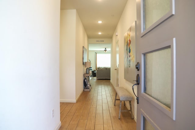 hallway featuring light wood-type flooring, baseboards, and recessed lighting