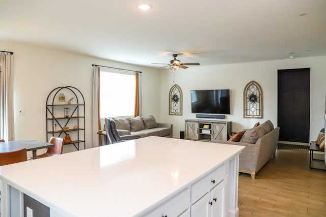 kitchen with white cabinets, light wood-style floors, ceiling fan, and open floor plan