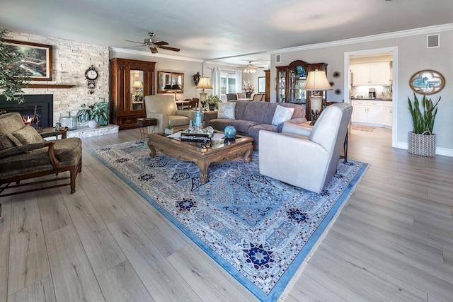 living room with light wood-style floors, a fireplace, and ornamental molding