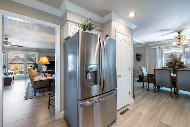 kitchen with crown molding, stainless steel fridge, white cabinets, and light wood-style floors