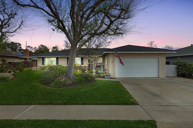 ranch-style home with an attached garage, fence, concrete driveway, stucco siding, and a front yard