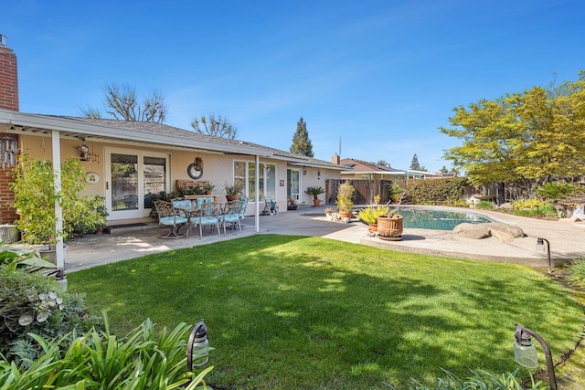 rear view of house featuring a yard, a patio, fence, and stucco siding