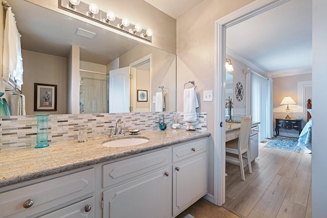 bathroom with a stall shower, wood finished floors, crown molding, vanity, and backsplash