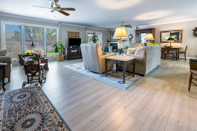 living area with light wood finished floors, a ceiling fan, and crown molding