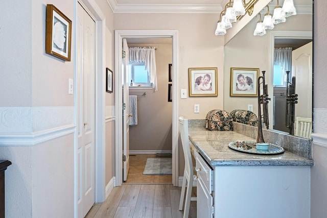 bathroom featuring baseboards, ornamental molding, wood finished floors, and vanity