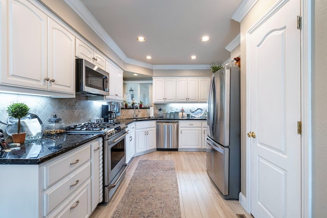 kitchen featuring stainless steel appliances, light wood-type flooring, a sink, and ornamental molding