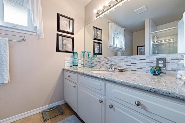 full bath featuring backsplash, a tile shower, vanity, baseboards, and tile patterned floors